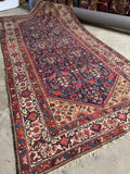 Antique 1920s Persian rug with navy blue ground and floral motifs.