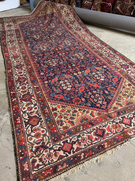 Antique 1920s Persian rug with navy blue ground and floral motifs.