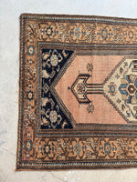 One end view of antique Persian area rug with dark blue spandrels and floral chain border.