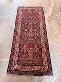 Red and navy Persian runner rug featuring a small-scale, spill-camouflaging pattern framed by a classic floral border.