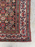 Antique Persian runner featuring S hook border motifs on ivory ground.