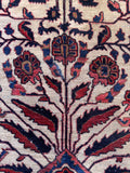 1920s vintage Persian Sarouk rug close-up showing intricate floral sprays, serrated leaves, and curling vines.
