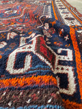 Vintage Shiraz rug from Persia showing scattered wear and low to medium wool pile.