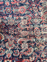 Close-up of antique Persian rug showing detailed Herati design with natural wool colors.