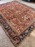 Antique Heriz tribal rug angled perspective showcasing rich vegetable-dyed colors and bold Northwest Persian craftsmanship.