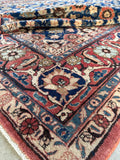 Detailed corner view of a 1940s Persian Veramin rug with layered floral border elements.