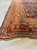 Corner view of antique Persian rug border with a rust red ground.