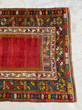Vintage tribal prayer rug with rich red center field and scattered antique wear.