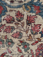 Close-up of a floral patterned rug texture with red, blue, and ivory colors.
