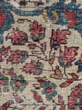 Close-up of a floral patterned rug texture with red, blue, and ivory colors.
