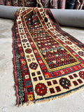 3x7 antique Caucasian runner rug with a dark field and colorful tribal motifs.