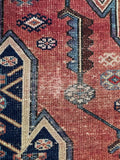 Rustic rust and navy blue rug close-up capturing aged vegetable dyes and scattered wear patterns.