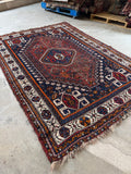 Antique tribal Persian Shiraz rug with navy blue ground and central diamond medallion.