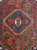 Close view of central medallion within larger diamond design on Shiraz tribal rug.