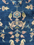 Close up of large antique Sparta carpet with floral motifs floating across a dark navy ground.