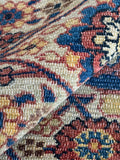 Close-up of a patterned rug with intricate designs in red, blue, and ivory.