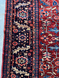 Detail of navy border with geometric floral motifs on Tabriz rug.