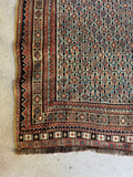 Corner detail of worn Afshar tribal rug with mellowed reds, blues, and soft ivory.