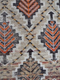 Low pile antique rug top-down view showing warm wheat field with orange and dark brown motifs.