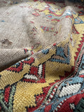 Antique tribal wool runner, early 1900s Caucasian rug with an ivory field, distressed farmhouse look, and bold geometric border pattern.