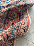 Close up view of antique Persian Veramin rug featuring coral floral borders.