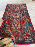 Handmade Persian Heriz rug. Small antique wool carpet with bold tribal design, dense weave, vibrant vegetable dyes, and authentic antique character.