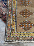 Corner view of antique vegetable dyed wool runner with geometric flowers and pops of orange throughout.