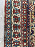 Low pile antique Caucasian Shirvan rug with rust, navy, ivory, and sky blue tones.
