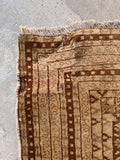 Antique vegetable dyed wool rug corner showing a professionally rewoven section and sturdy selvage edge.