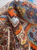 Shiraz tribal wool rug featuring geometric diamond motifs in orange and dark blue.