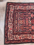 Vintage 1920s Persian hallway runner top-down view showing a detailed floral border and busy geometric design.