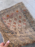 Rustic tribal area rug flat lay showing worn edges, low pile, and authentic antique condition.