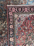 Vintage Ferahan rug corner detail highlighting a dark navy border filled with intricate pink and blue florals.