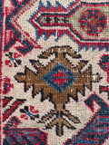 Close up of an authentic vintage Caucasian rug with a bold geometric tribal pattern.