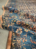 Antique rug showcasing stylized florals and vibrant hues of indigo, turquoise, and sage