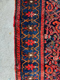 Edge and border view of antique Persian rug with strong color contrast and floral motifs.