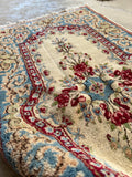 Plush wool Persian Kerman rug showing its thick full pile and flexible handle.