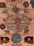 Blush field Heriz rug with bold tribal medallions and blossoms.