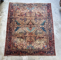 Full view of antique Persian Heriz rug with bold geometric medallion on ivory ground