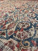Close-up of a patterned rug with intricate designs in red, blue, and ivory.