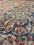 Close-up of a patterned rug with intricate designs in red, blue, and ivory.