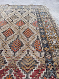 Small antique rug flat lay displaying diamond geometric patterns and natural age-related character.