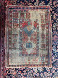 Antique Caucasian tribal rug featuring bold geometric village motifs in worn vegetable-dyed wool.