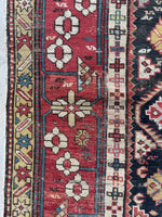 Caucasian rug with brick red border and floral chain design.