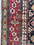 Caucasian rug with brick red border and floral chain design.