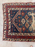 Small antique accent rug featuring a striking blue field and intricate blossom motifs.
