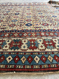 Vintage tribal wool rug with repeating geometric motifs and strong symmetry.