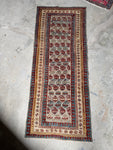Full view of antique Caucasian runner with boteh motifs on a sandy ivory field.
