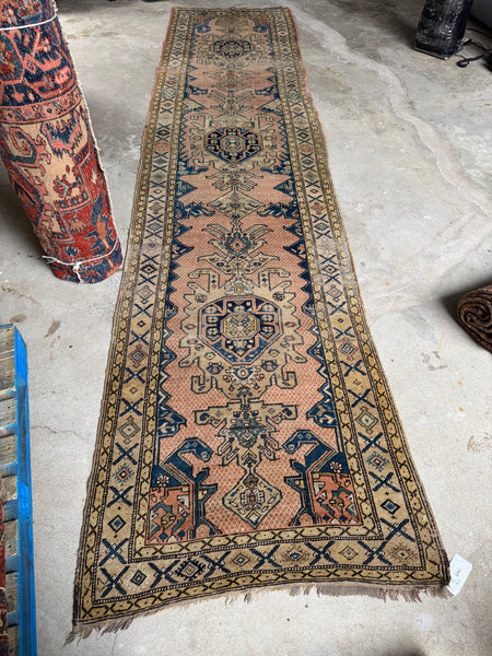 Full body view of antique Caucasian runner laid flat on floor.