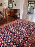 Navy blue Persian rug with repeating pink blossom and star-shaped flower field.